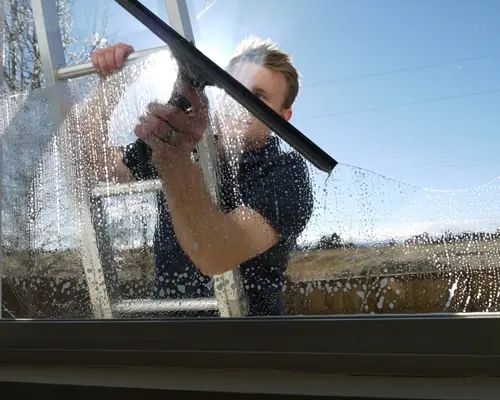 Window cleaner using a squeegee on exterior glass