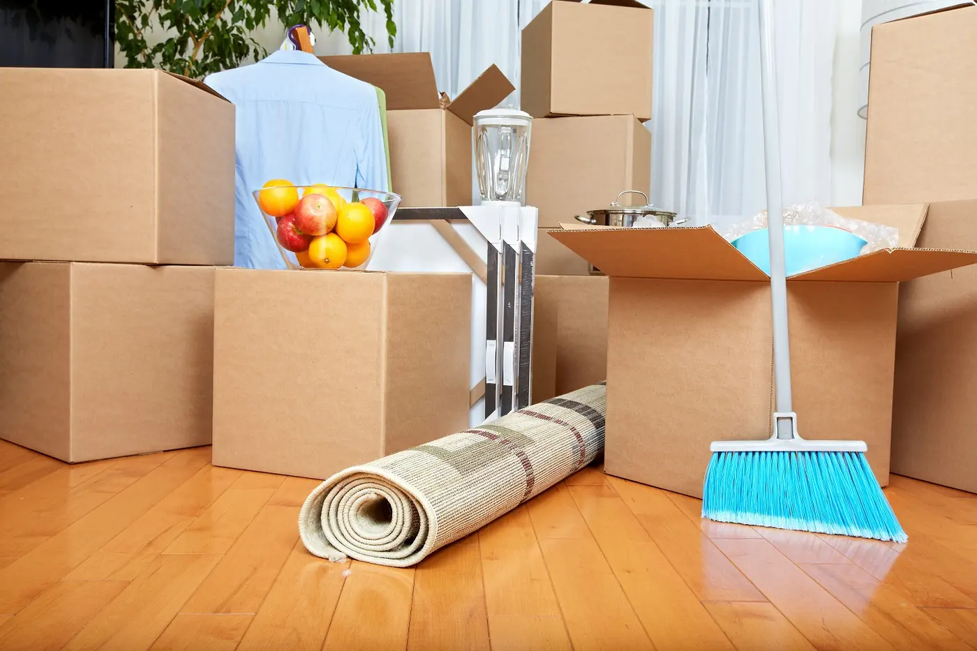 Packed boxes, a rolled rug and cleaning tools in a room