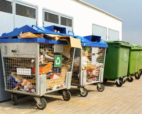 Cardboard and bags beside outdoor recycling containers